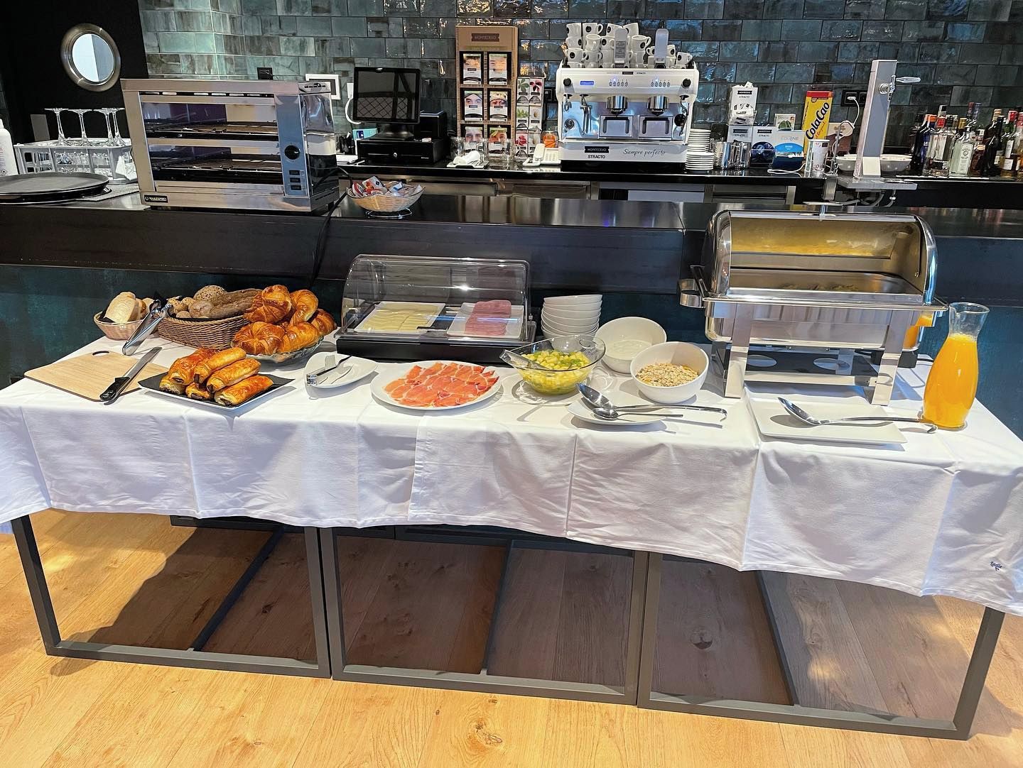 A buffet setup with various food items, a coffee machine, and a juice dispenser.