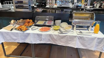 A buffet setup with various food items, a coffee machine, and a juice dispenser.