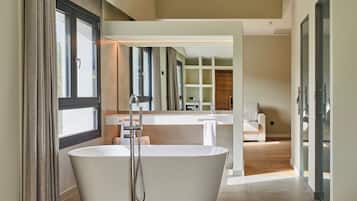 Un baño moderno con una bañera independiente, un espejo grande y suelo de madera.