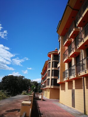 A multi-story building with balconies, a paved walkway, and a clear blue sky. - Apartamentos Gran Socaire De Noja (Noja)