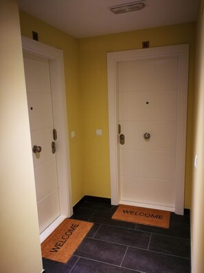Un pasillo con dos puertas, cada una con un tapete que dice 'WELCOME'.