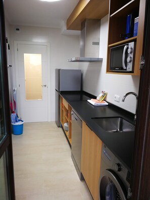 Una cocina compacta con microondas, pileta y lavavajillas.