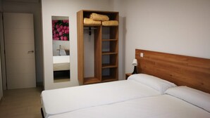 Un dormitorio con una cama, un armario de madera, una mesita de noche y un estante en la pared.