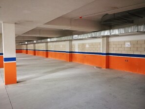 Un aparcamiento con múltiples plazas, suelos de hormigón y paredes pintadas de naranja y azul.