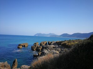 A coastal landscape with rocky outcrops and a clear view of the sea and distant mountains. - Apartamentos Gran Socaire De Noja (Noja)