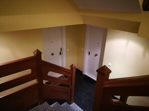 Una escalera con barandas de madera que lleva a un rellano donde se ven dos puertas blancas.