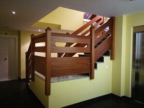 A wooden staircase with a handrail leading to a landing. - Apartamentos Gran Socaire De Noja (Noja)