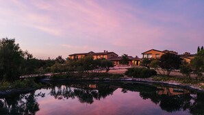 A serene lakeside property with multiple buildings, a clear reflection in the water, and a well-maintained garden. - Abba Las Viñas Tiedra Hotel Rural (Tiedra)