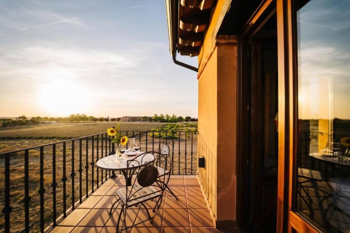Un balcon avec une table dressée pour deux personnes, donnant sur un vignoble.