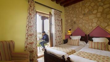 Habitación de hotel con dos camas, una silla y vistas al exterior.