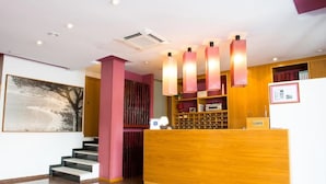 A reception area with a wooden desk, a staircase, and a large abstract painting on the wall. - Celymar (Benidorm)