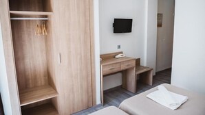 A hotel room with a wooden wardrobe, a desk with a flat-screen TV, and two beds. - Celymar (Benidorm)