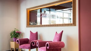 A room with two plush, pink chairs, a small side table with a potted plant, and a large mirror with a gold frame. - Celymar (Benidorm)