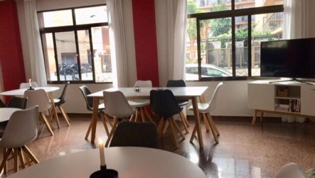 A dining area with tables and chairs, large windows, and a television. - Celymar (Benidorm)