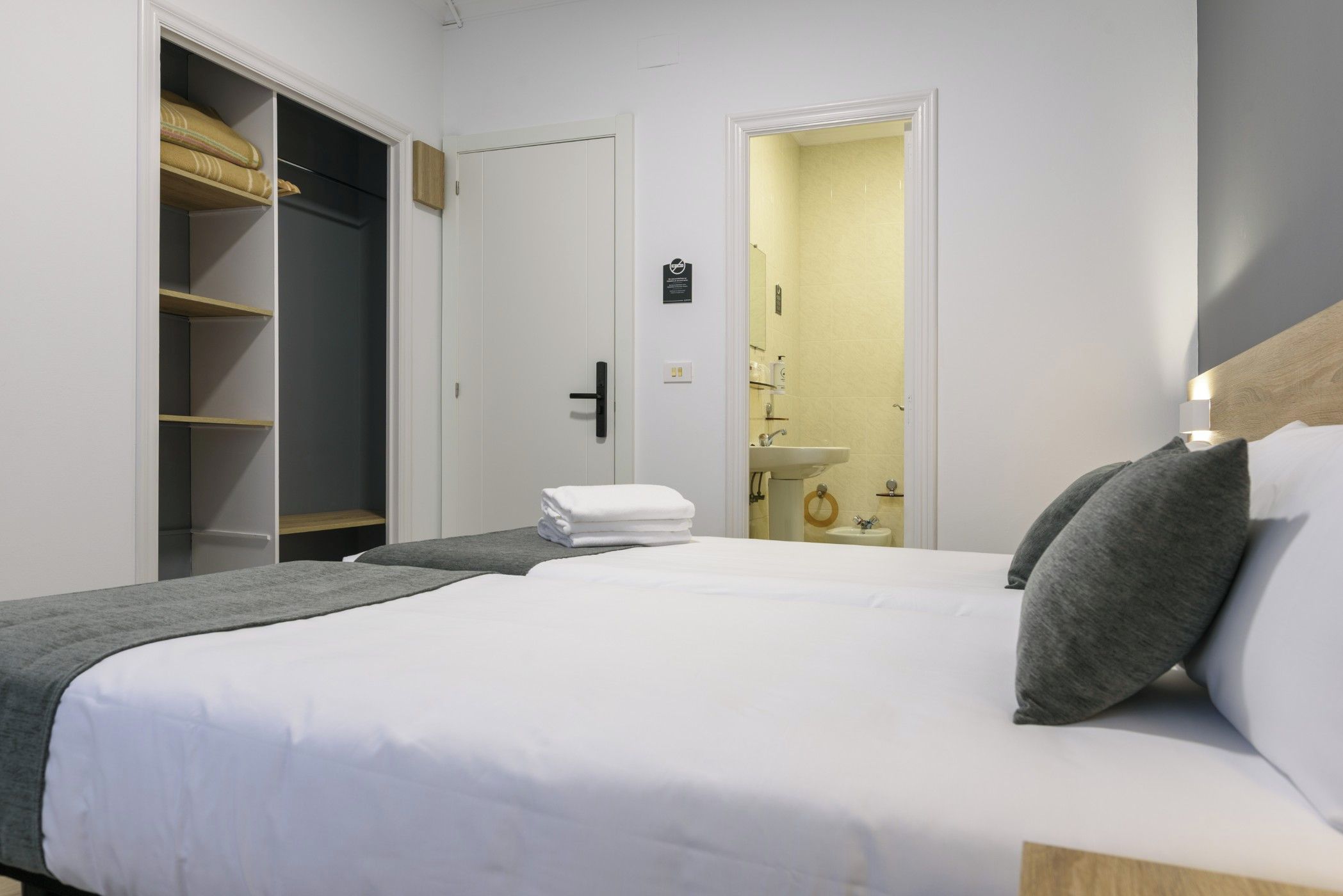 A hotel room with a large bed, a wardrobe, and a bathroom visible through an open door.