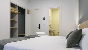 Et hotelværelse med en stor seng, et skab og et badeværelse, der kan ses gennem en åben dør.