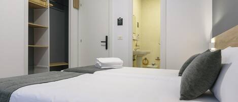 A hotel room with a large bed, a wardrobe, and a bathroom visible through an open door.