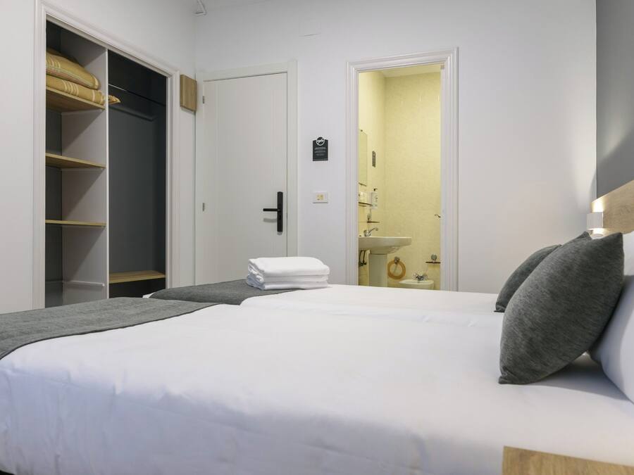 A hotel room with a large bed, a wardrobe, and a bathroom visible through an open door.