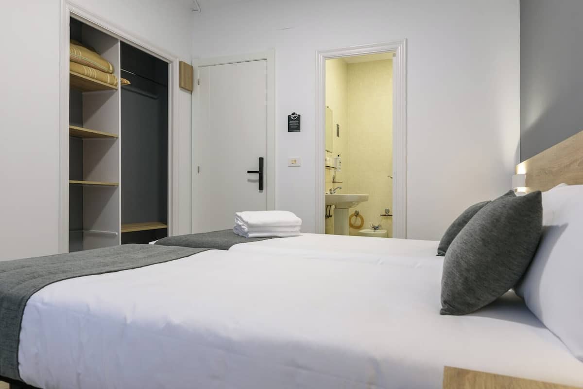A hotel room with a large bed, a wardrobe, and a bathroom visible through an open door.