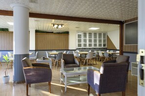 A spacious dining area with modern furniture, including chairs and tables, and a large window providing natural light.