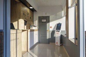 A reception area with a wooden counter, a door, and a self-service kiosk.