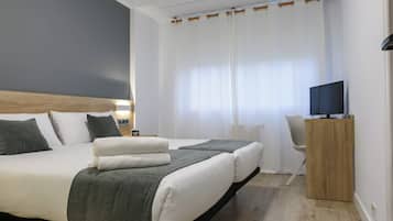 Una habitación de hotel moderna con una cama grande, un televisor sobre un soporte de madera y un escritorio con una silla.