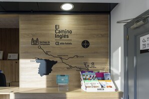 A wooden wall with a map of El Camino Ingles, a hotel sign, and a display of travel brochures. - Alda Narón (Naron)