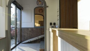 Ein Empfangsbereich mit Holztresen, Glastür und einer kleinen Treppe zu einer erhöhten Ebene.