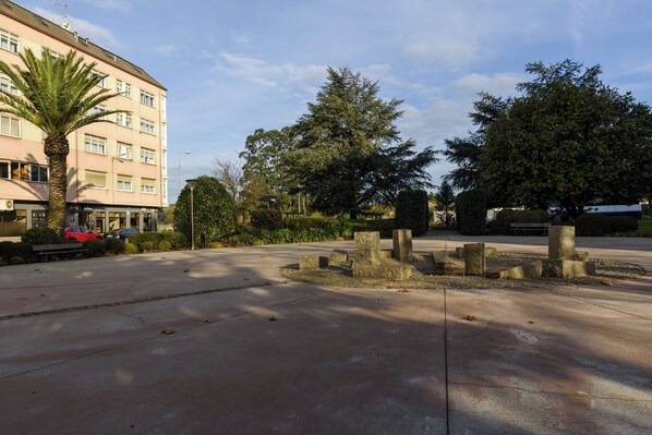 Un espace de stationnement agrémenté d’un palmier, un bâtiment doté de nombreuses fenêtres et une structure en pierre.