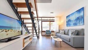 A modern living room with a flat-screen TV, a grey sofa, a coffee table, and a staircase. - Villagrancanaria (Mogan)