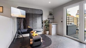 A modern living room with a large TV, a fireplace, a dining area, and a view through a glass door. - Modern & Spacious with Wellness (Kortrijk)