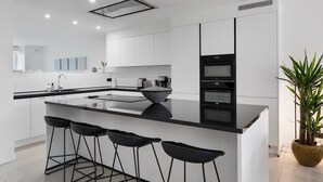 A modern kitchen with white cabinets, a black countertop, and a central island with bar stools. - Modern & Spacious with Wellness (Kortrijk)