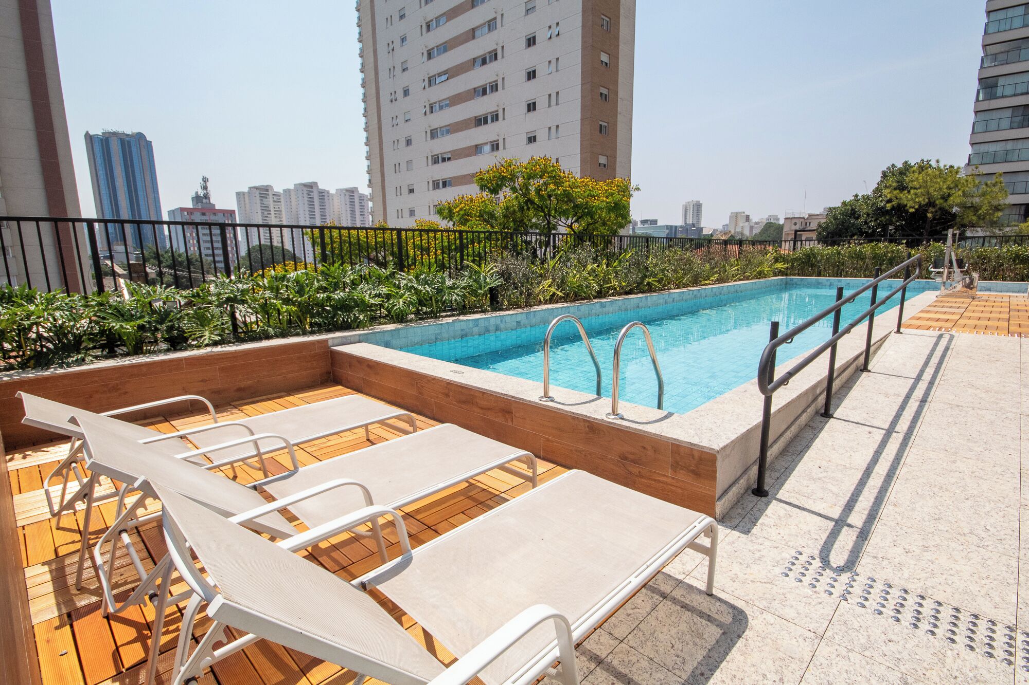 A rooftop pool with lounge chairs and a view of surrounding buildings.