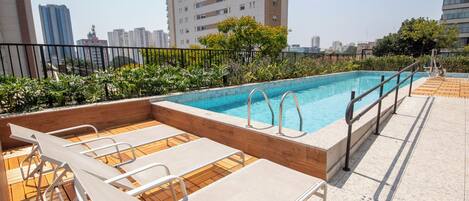 A rooftop pool with lounge chairs and a view of surrounding buildings.