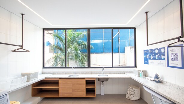A modern kitchen with a large window, wooden cabinets, and a sink. - Perdizes Smart Experience - Allianz (São Paulo)