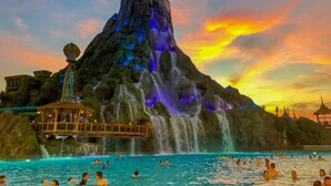 Eine große Felsformation mit Wasserfällen und einem Pool, in dem Menschen schwimmen.