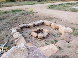 A circular stone fire pit surrounded by rocks in a rural setting. - Cabin get-away in the Unaweep Canyon (Whitewater)
