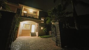 Ein zweistöckiges Haus mit Balkon, geschlossenem Eingangstor und einem gepflasterten Auffahrt.