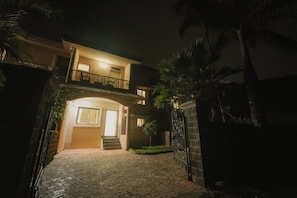 Een huis met twee verdiepingen, een balkon, een hek en een geplaveid pad.