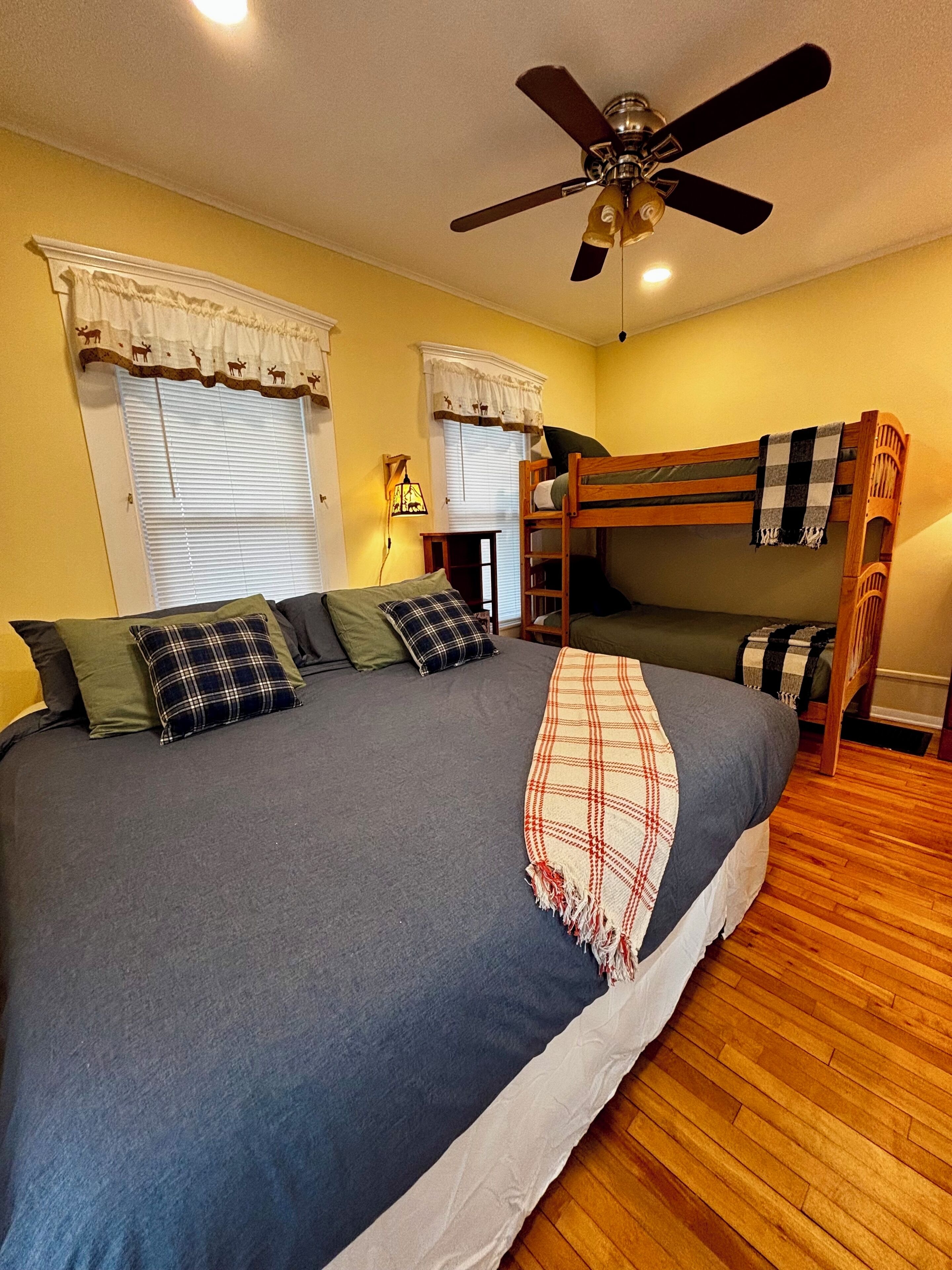 Un dormitorio con una cama litera, una cama individual y un ventilador de techo.