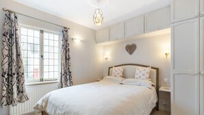 Un dormitorio con cama, cortinas, una lámpara en la pared y un radiador.