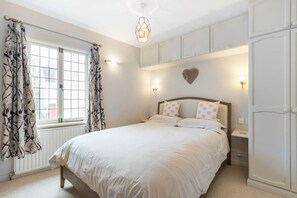 A bedroom with a bed, curtains, a wall-mounted light, and a radiator. - Stylish Victorian Cottage in Central Richmond (Richmond)