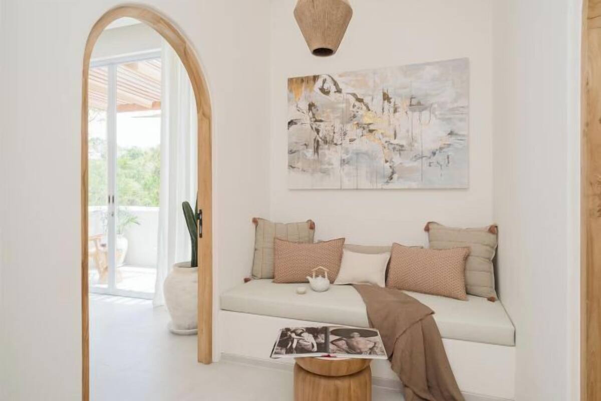 A modern living room with a white sofa, a wooden archway, and a large abstract painting on the wall.