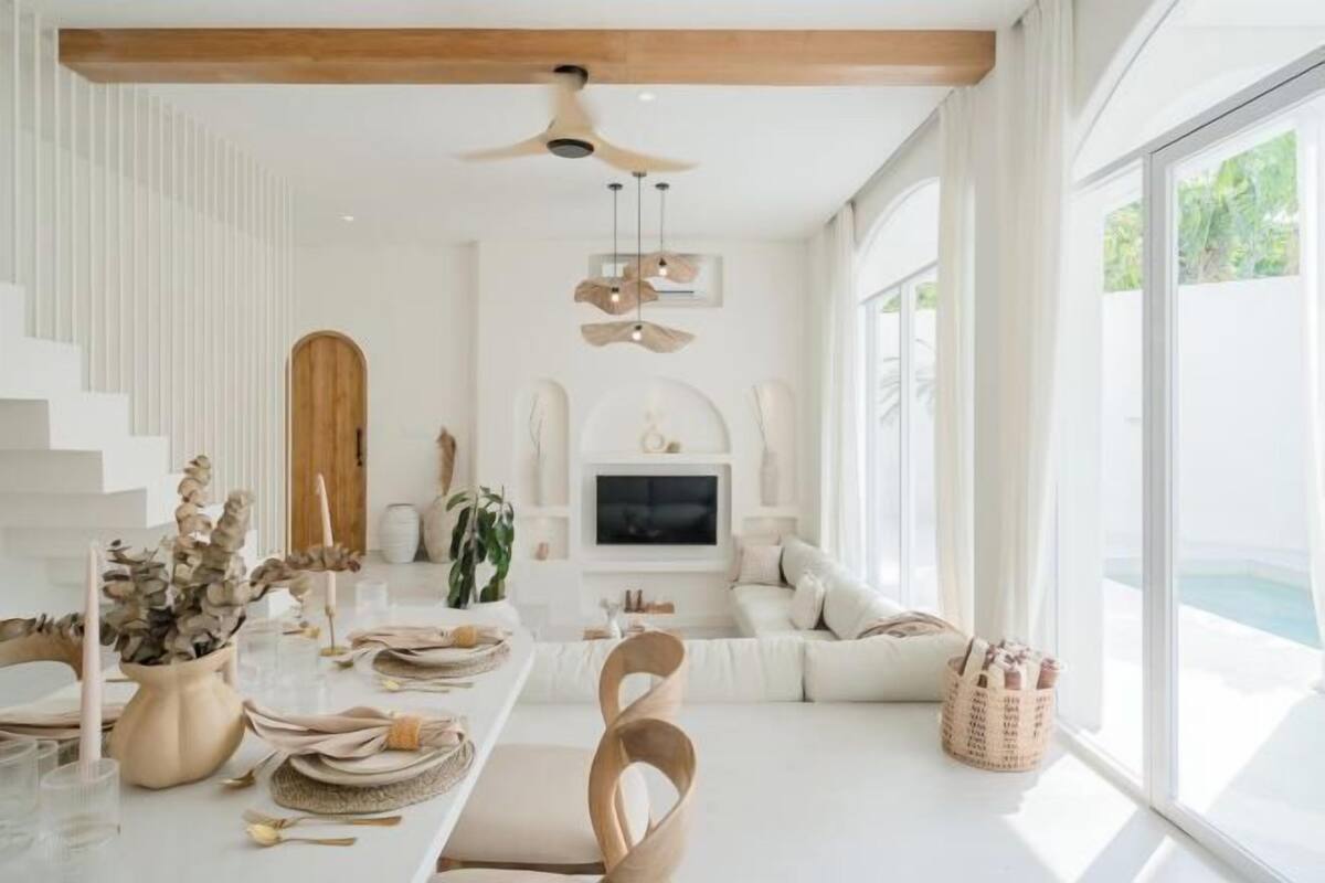 A modern interior with a dining area, a sofa set, a TV, and a large window.