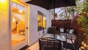 An outdoor patio with a glass door leading to a staircase, a table with chairs, and string lights. - Walk to Downtown Paso & Sip Local Wine Under the Stars Casa Robles by Avantstay (Paso Robles)