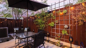 An outdoor patio with a table and chairs, a wooden fence, and string lights. - Walk to Downtown Paso & Sip Local Wine Under the Stars Casa Robles by Avantstay (Paso Robles)