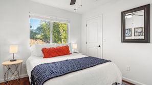 A bedroom with a bed, a window, a door, a bedside table, and a wall-mounted mirror. - Walk to Downtown Paso & Sip Local Wine Under the Stars Casa Robles by Avantstay (Paso Robles)