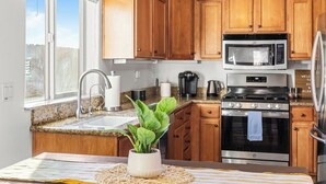 A kitchen with wooden cabinets, a stainless steel sink, a microwave, a stove, and a refrigerator. - Walk to Downtown Paso & Sip Local Wine Under the Stars Casa Robles by Avantstay (Paso Robles)