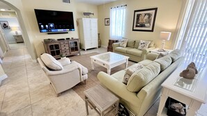 A living room with a sofa, armchairs, a coffee table, a TV, and a ceiling fan. - TOP FLORIDA's Villa Porto Vista (Cape Coral)