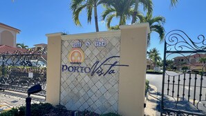 A sign with the name "PORTO Vista" and a decorative palm tree logo, surrounded by a fence and palm trees. - TOP FLORIDA's Villa Porto Vista (Cape Coral)